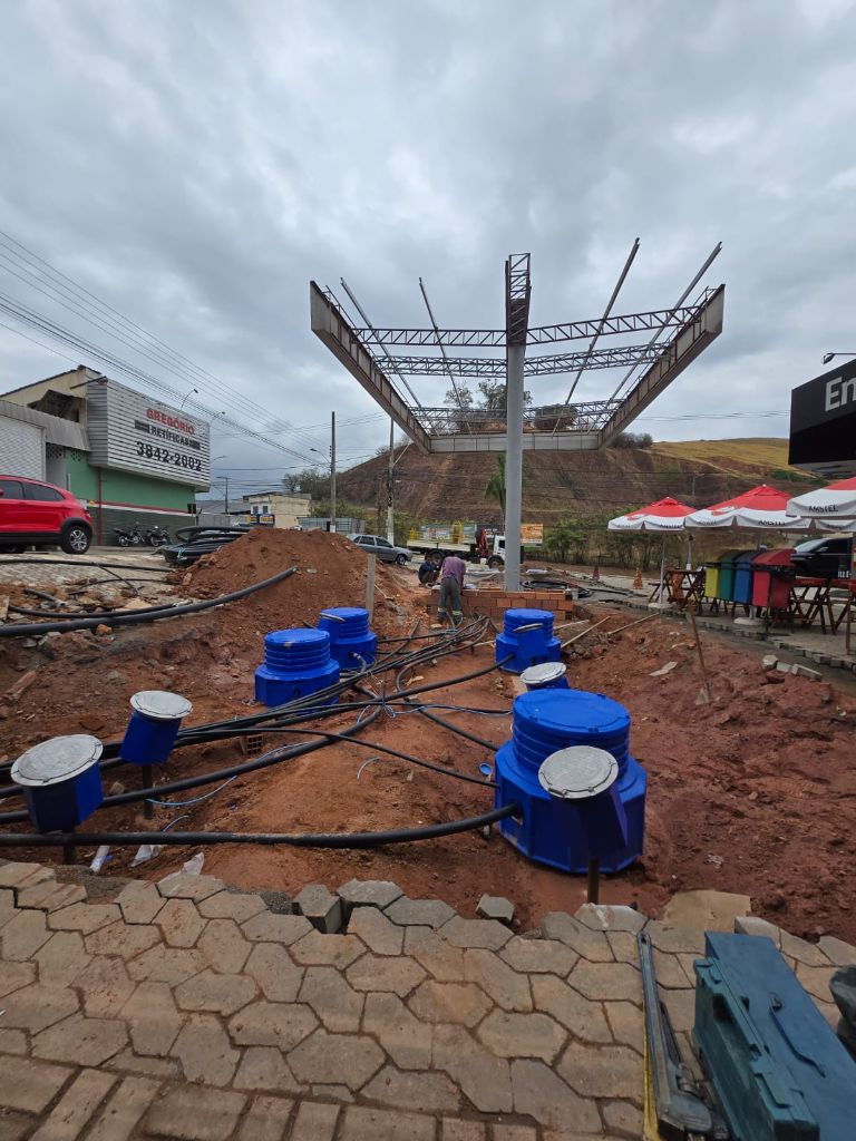 Tanque subterrâneo laranja sendo instalado em vala com areia